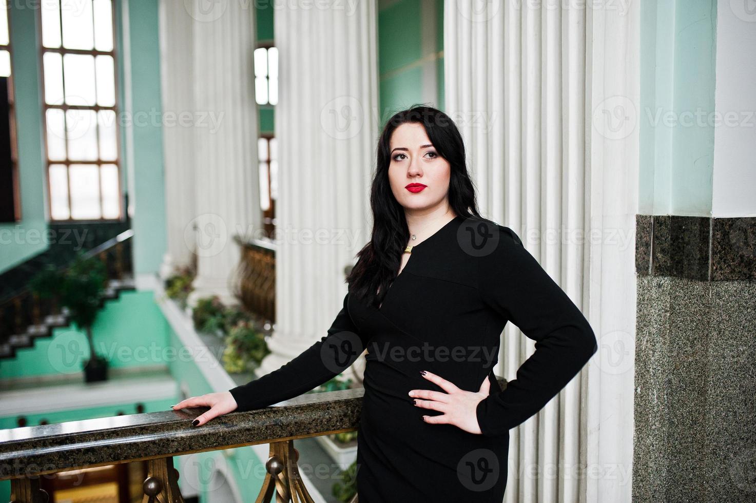 menina morena de vestido preto na estação ferroviária interior. foto