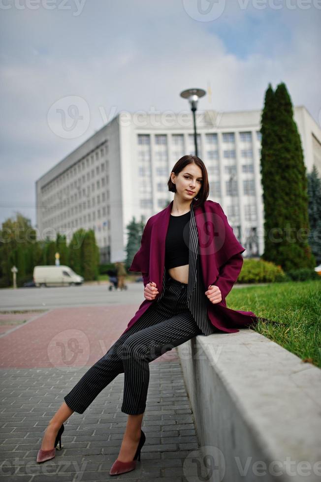 uma mulher modelo jovem bonita e elegante de pernas altas no casaco clarete. foto