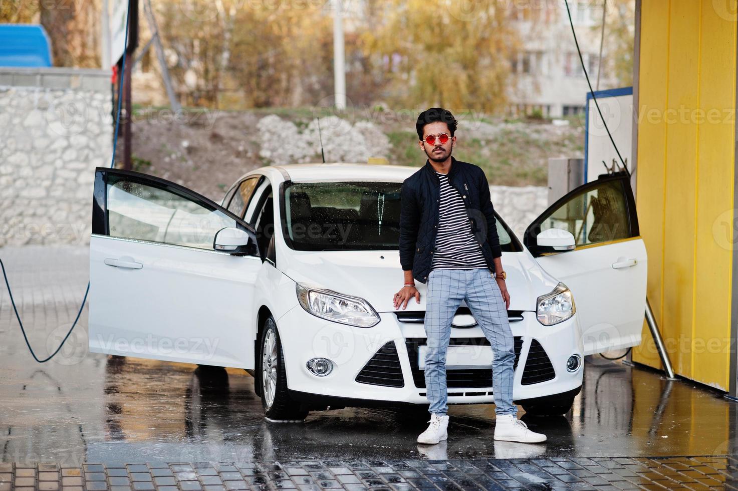 homem do sul da Ásia ou homem indiano lavando seu transporte branco na lavagem de carros. foto