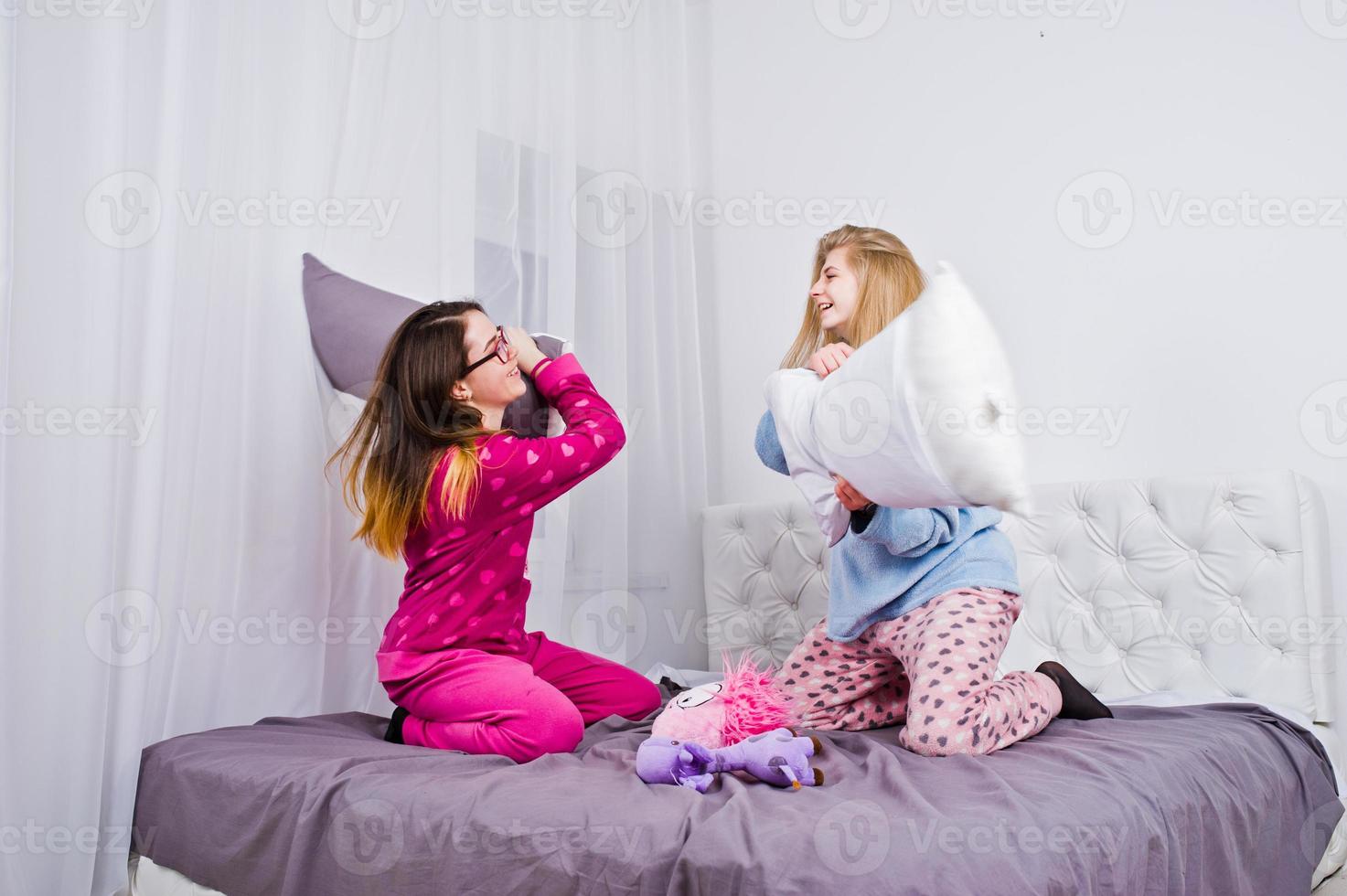 duas amigas garotas de pijama se divertindo na cama no quarto. foto