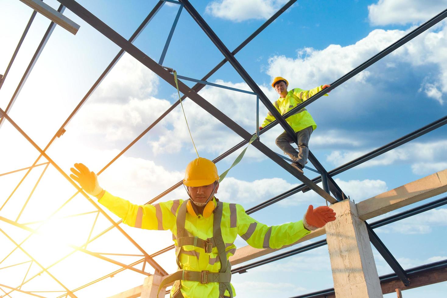 os trabalhadores da construção civil usam cintos de segurança e cintos de segurança trabalhando em telhados metálicos industriais. foto