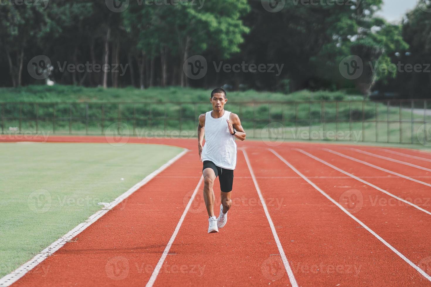 atleta esportista corredor treinamento executado na pista no estádio de manhã. homem corredor vestindo colete branco para praticar corrida prepare-se para corrida de competição. conceito de esporte. foto