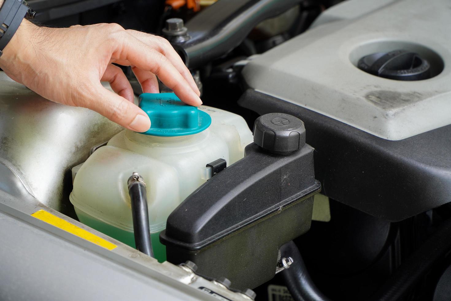 mecânico inspeciona o tanque de expansão com anticongelante verde. nível do líquido de arrefecimento do veículo no sistema de radiador do carro. autopeças foto