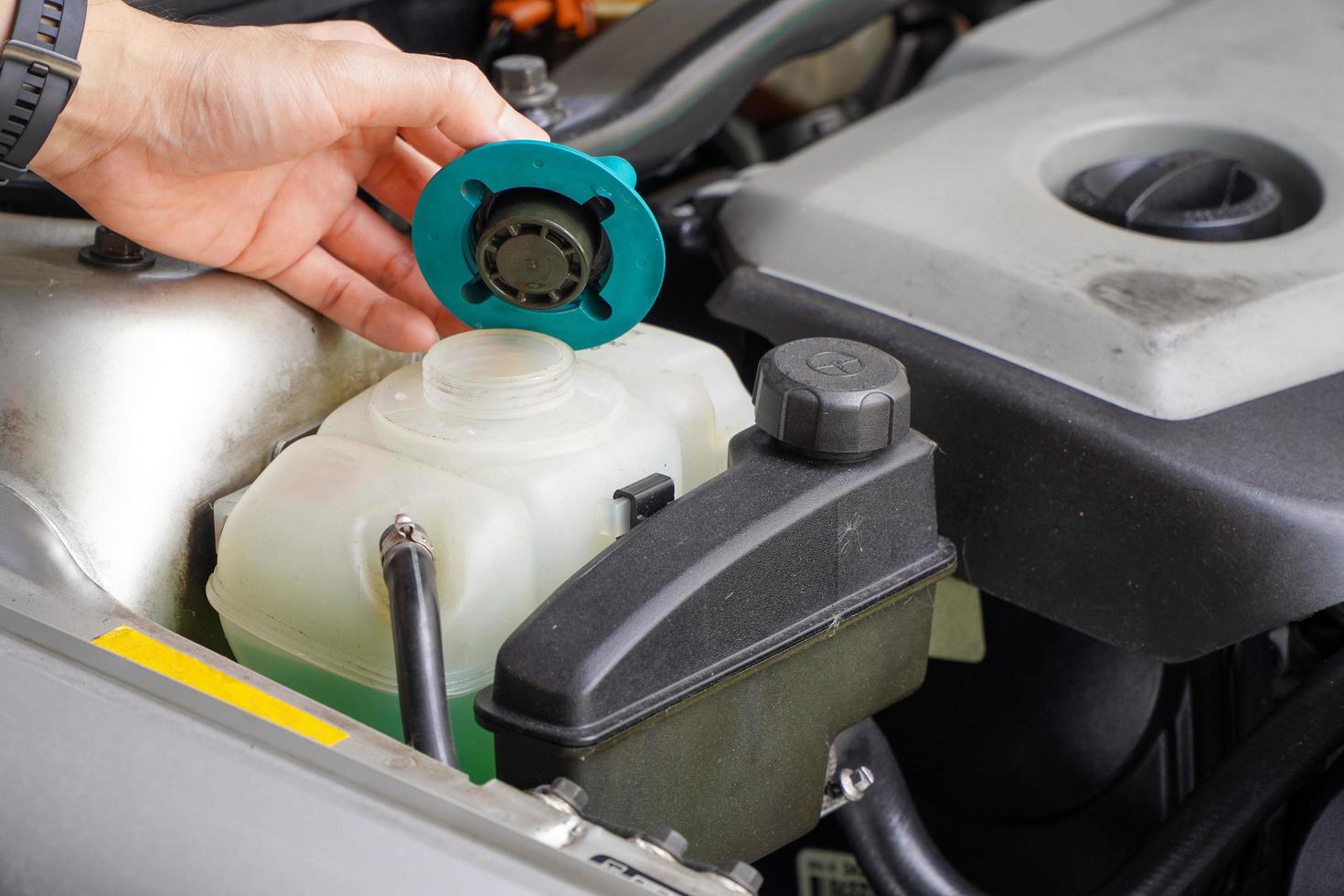 mecânico inspeciona o tanque de expansão com anticongelante verde. nível do líquido de arrefecimento do veículo no sistema de radiador do carro. autopeças foto