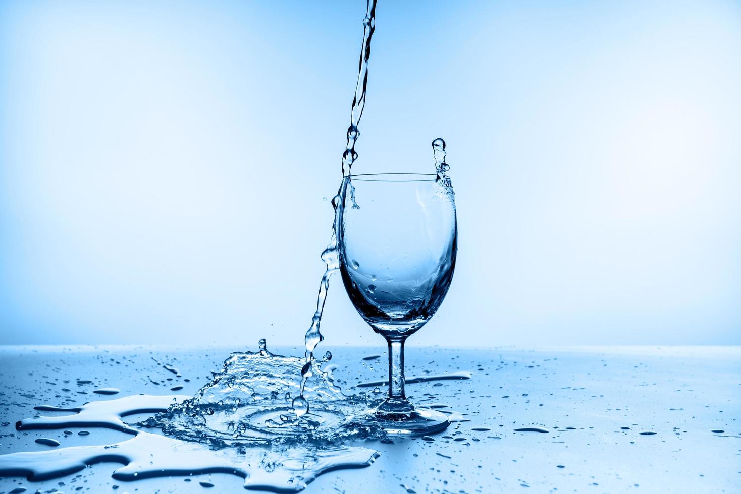 água espirrando de vidro isolado em fundo azul foto