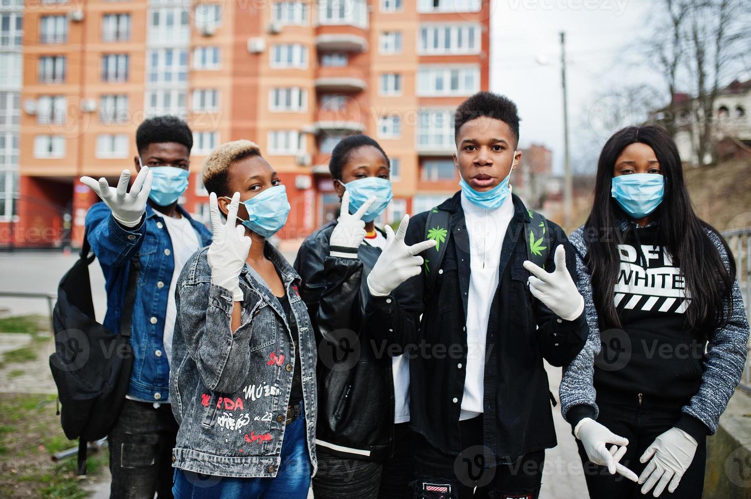 grupo de amigos adolescentes africanos contra a rua vazia com construção usando máscaras médicas protegem contra infecções e doenças quarentena de vírus coronavírus. foto