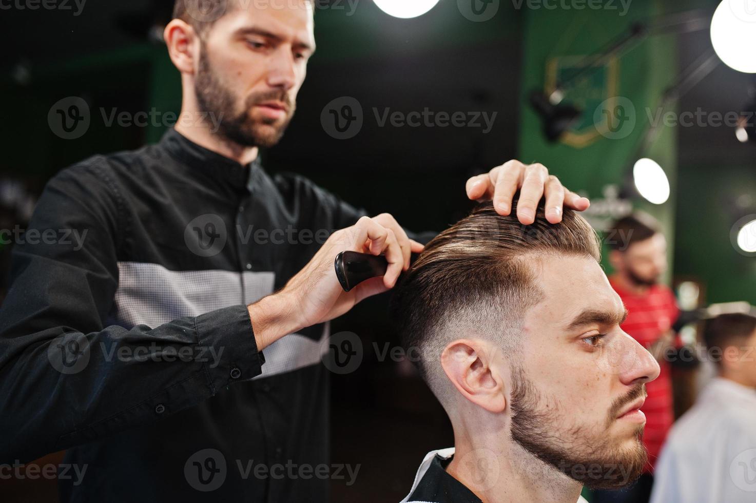 homem barbudo bonito na barbearia, barbeiro no trabalho. foto