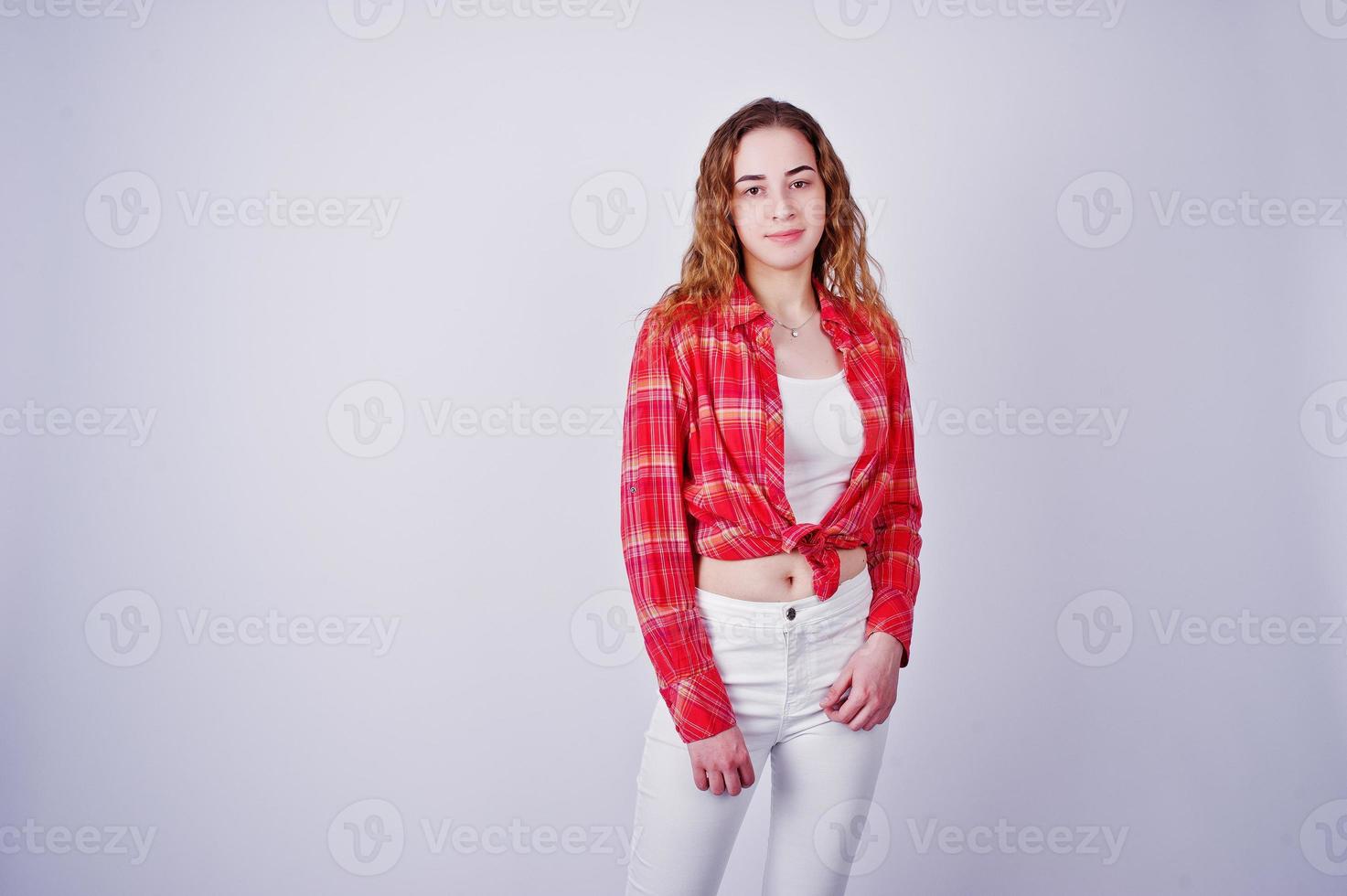 jovem de camisa vermelha e calça branca contra um fundo branco no estúdio. foto