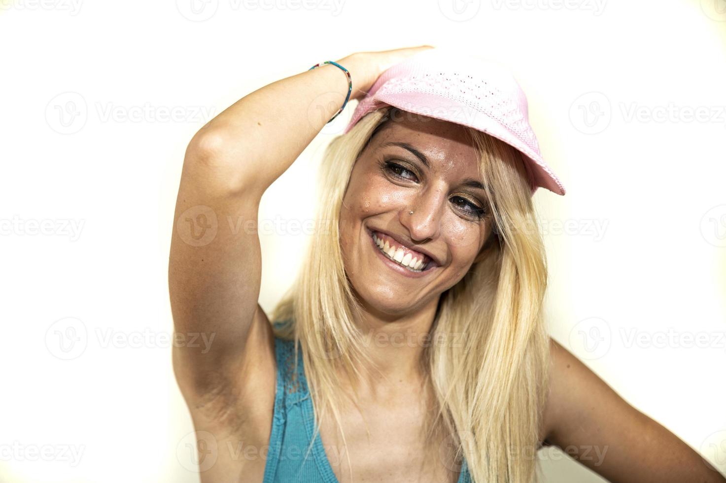 menina loira de chapéu rosa sorri com as mãos no chapéu rosa foto