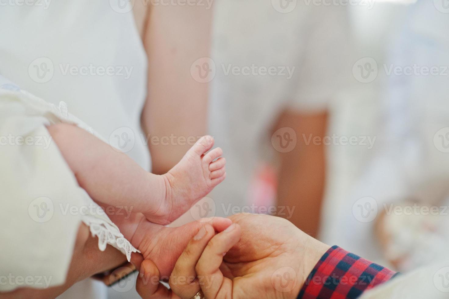 pernas de bebê recém-nascido na cerimônia de batismo na igreja. foto