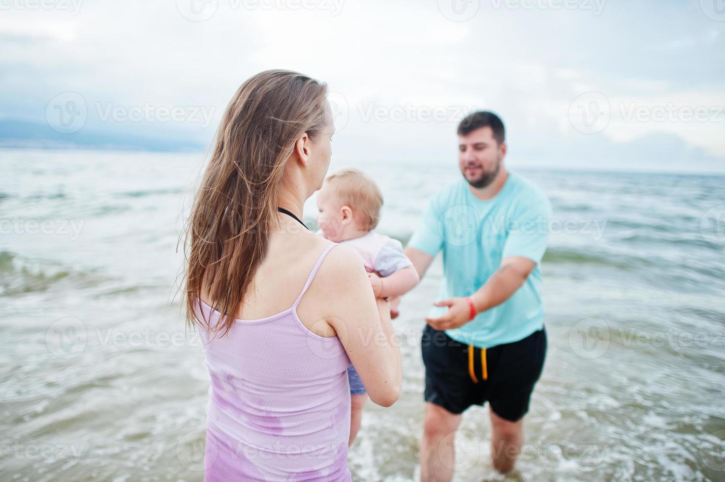 férias de verão. pais e pessoas atividade ao ar livre com crianças. boas férias em família. pai, mãe grávida, filha bebê na praia de areia do mar. foto