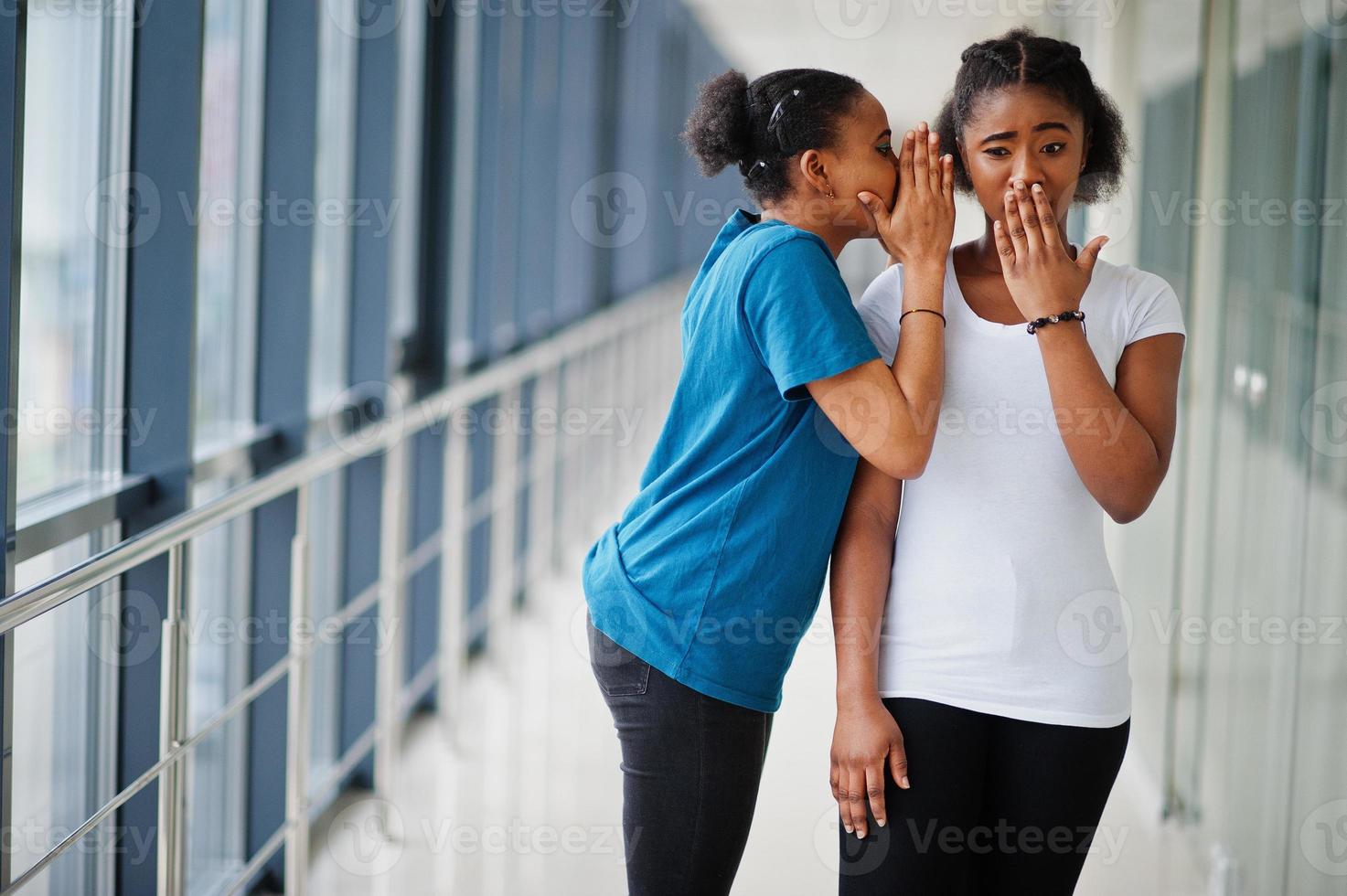 duas amigas africanas em camisetas sussurram fofocas internas juntas. foto