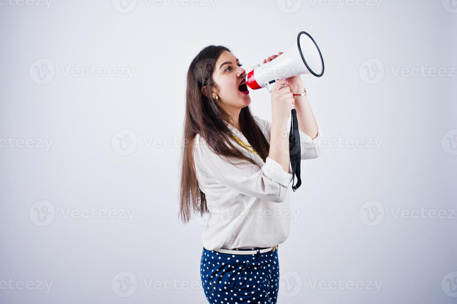 retrato de uma jovem de calça azul e blusa branca posando com megafone no estúdio. foto