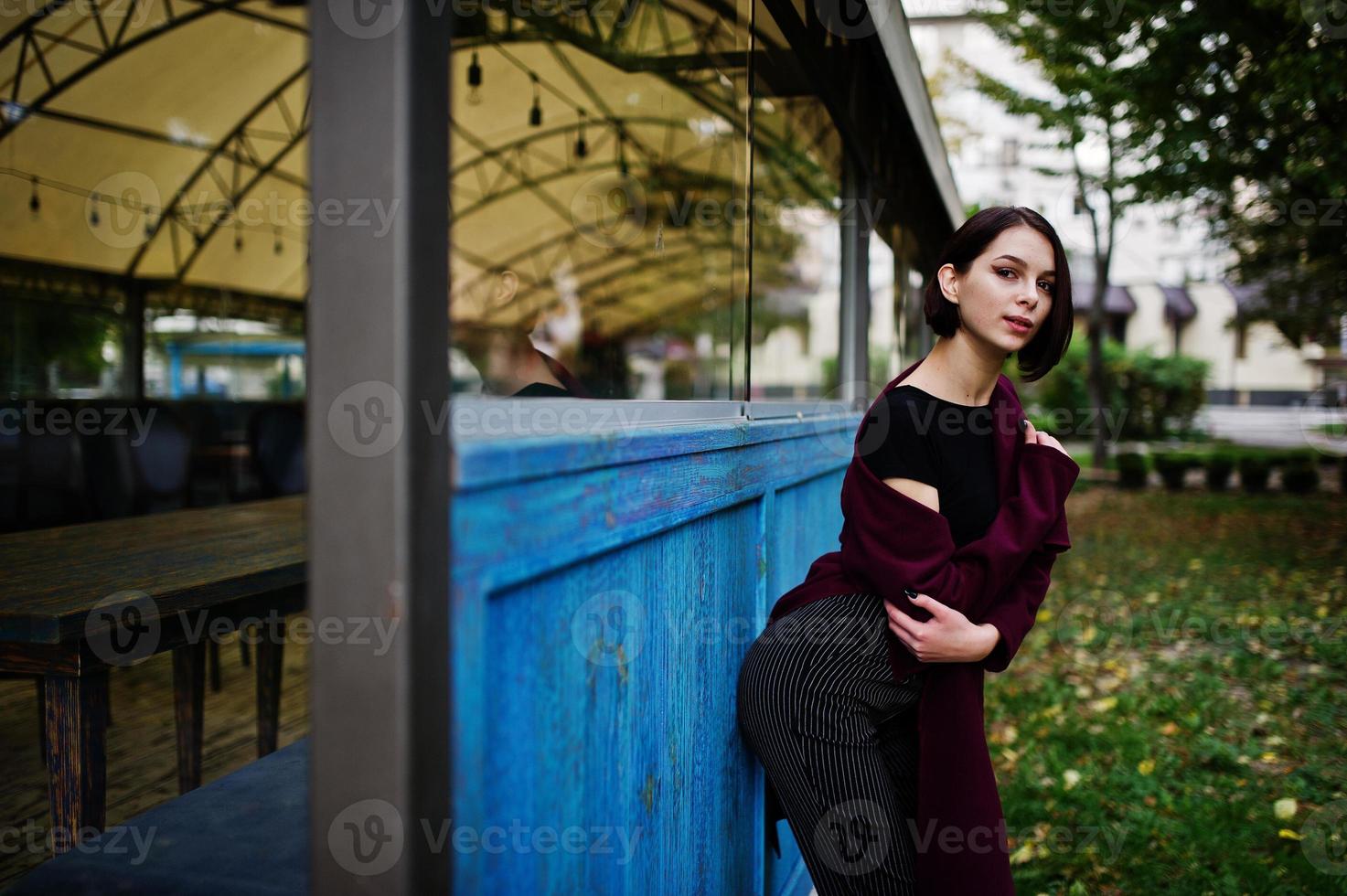 uma mulher modelo jovem bonita e elegante de pernas altas no casaco clarete. foto