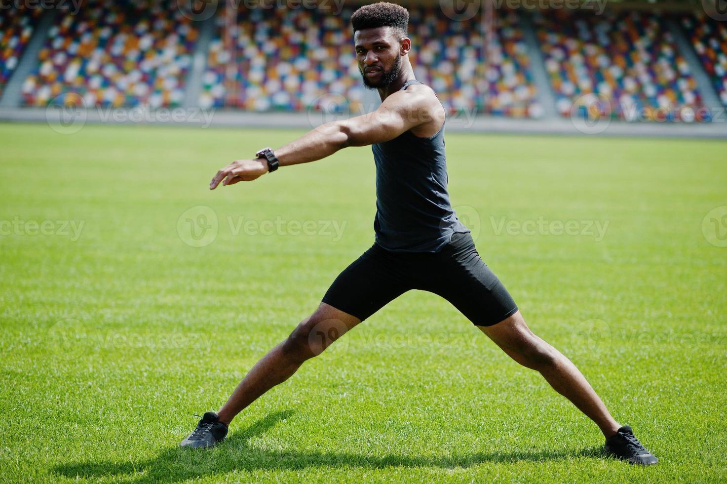 atleta masculino americano africano em roupas esportivas fazendo exercícios de alongamento no estádio. foto