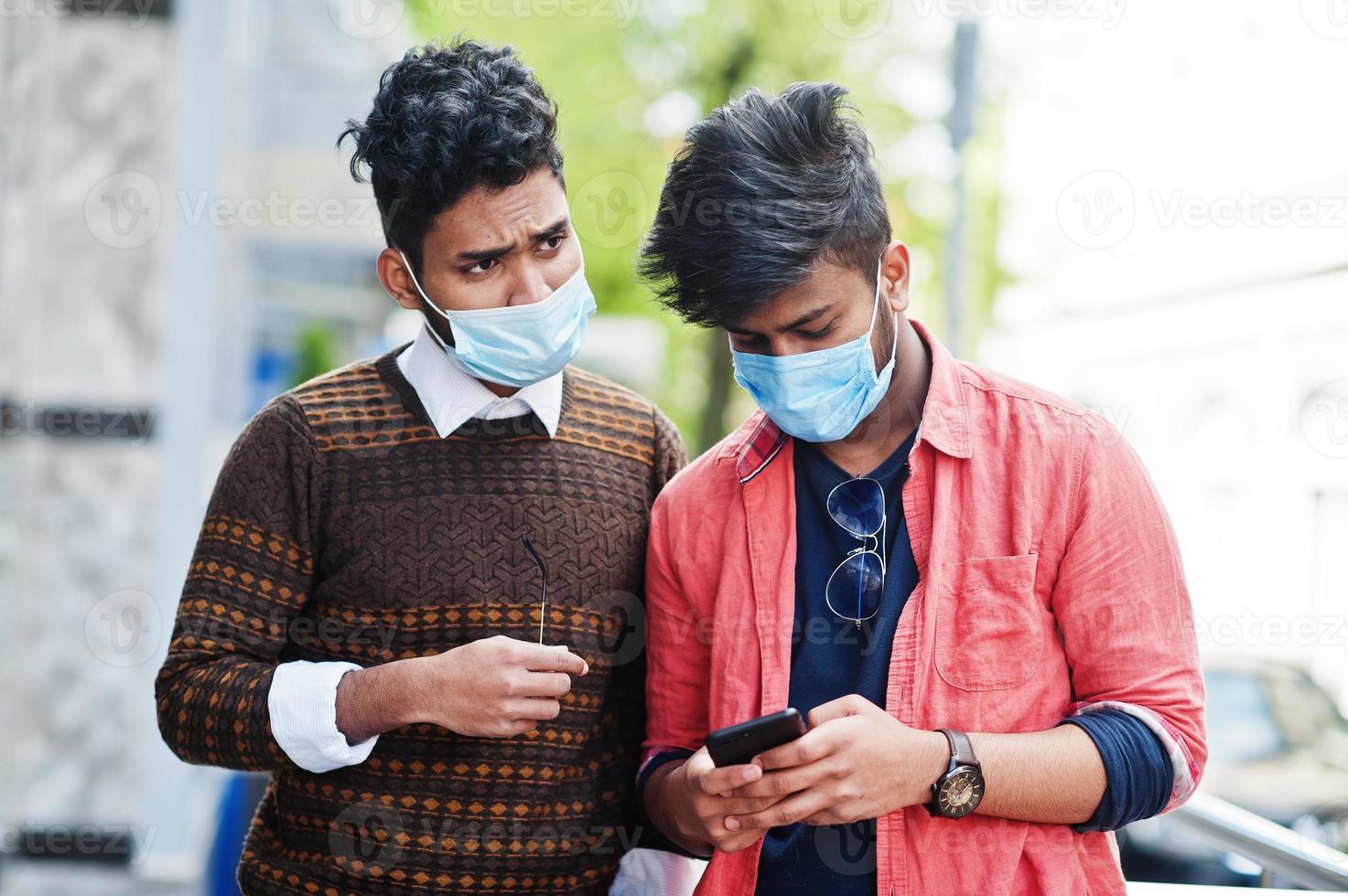 conceito de coronavírus covid-19. dois indianos do sul da Ásia usando máscara para proteger do vírus corona olhando para o celular. novo estilo de vida normal pós pandemia na índia. foto