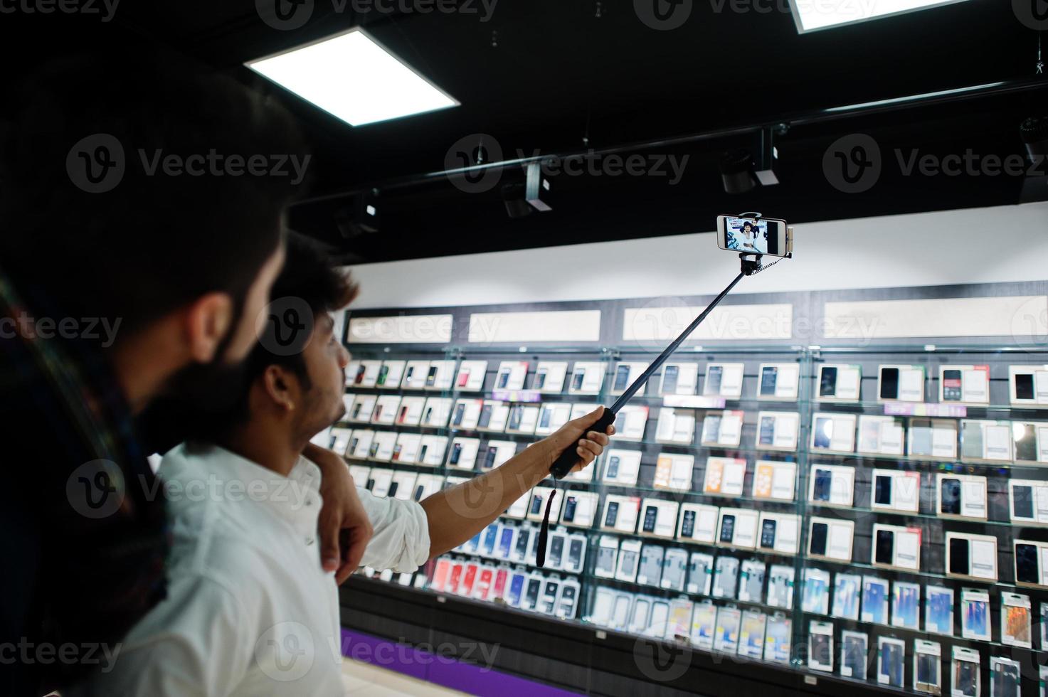 dois índios mans comprador de cliente no celular fazendo selfie por vara monopé. conceito de povos e tecnologias do sul da Ásia. loja de celulares. foto