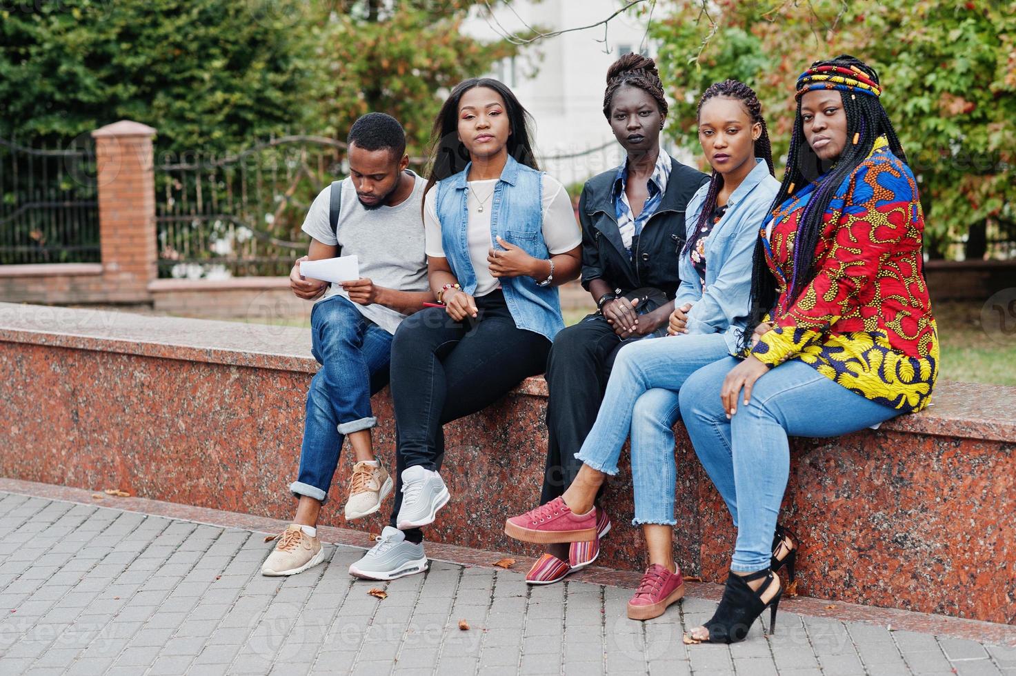 grupo de cinco estudantes universitários africanos passando tempo juntos no campus no pátio da universidade. amigos negros afro estudando. tema educação. foto