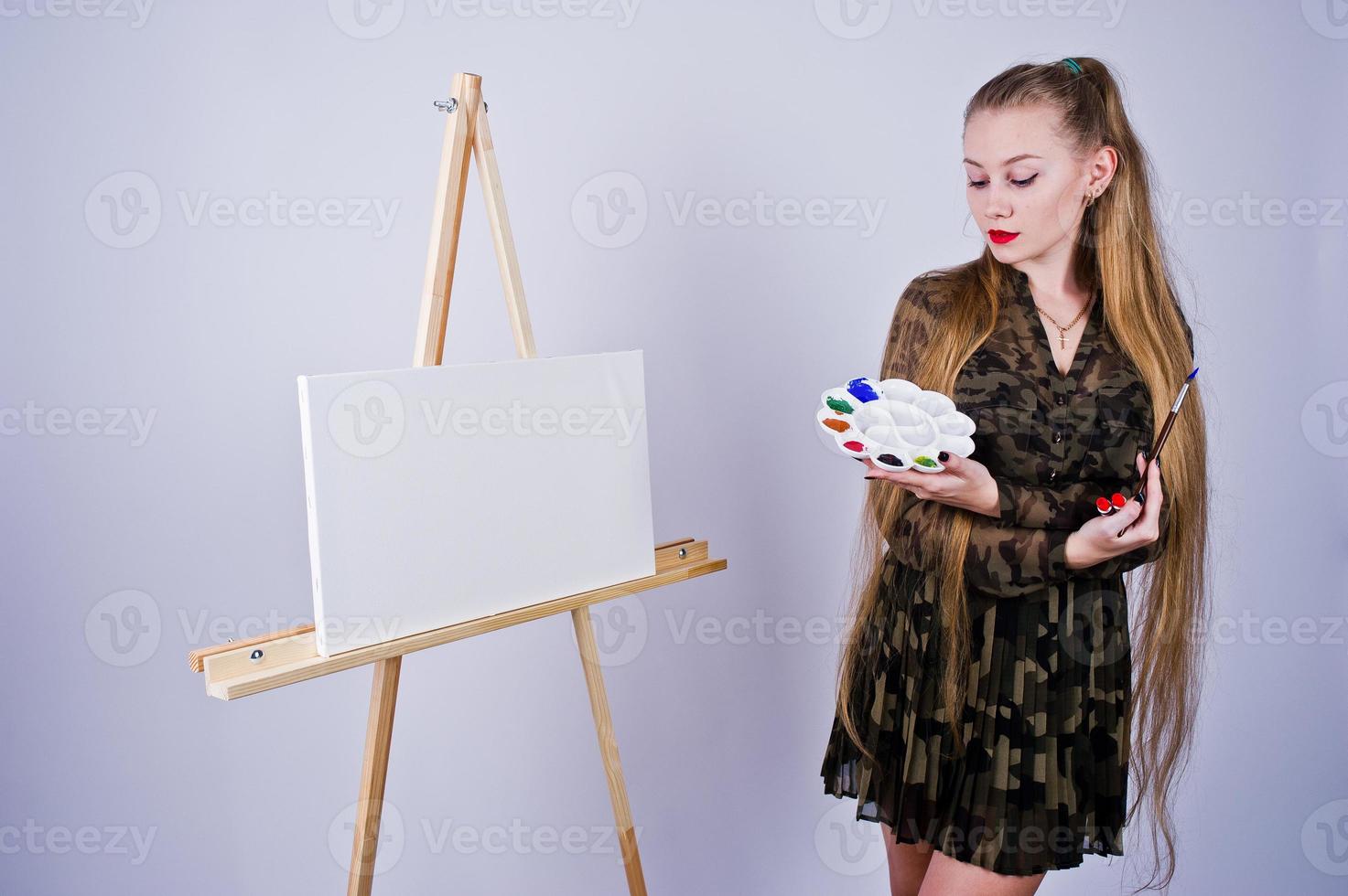 pintor de artista de mulher bonita com pincéis e tela a óleo posando em estúdio isolado no branco. foto