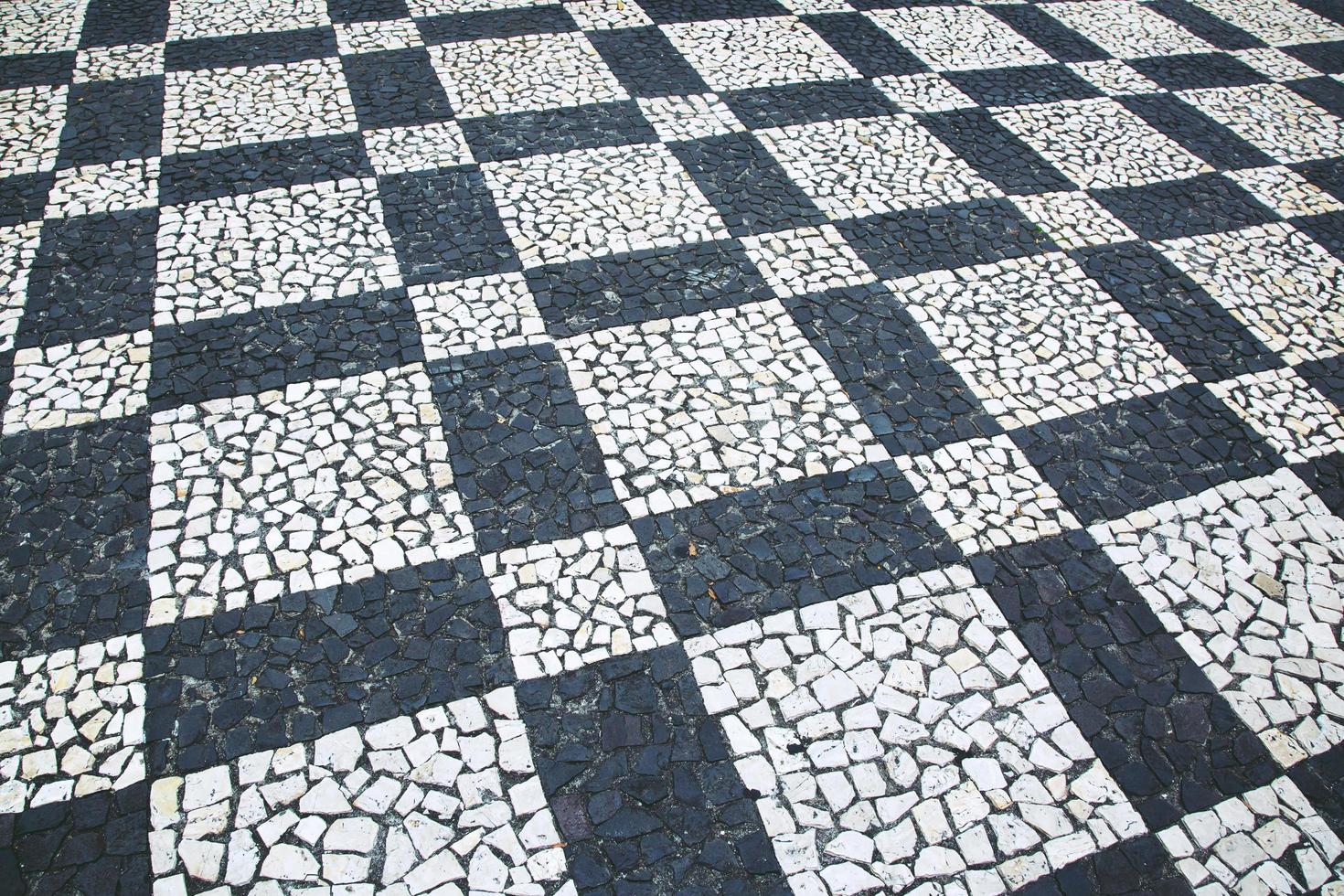 antiga rua estrada pavimentada superfície pedra pavimento passarela textura padrão chess board. fundo de pavimento de paralelepípedos de granito. abstrato da velha Europa de estilo vintage de pavimento de paralelepípedos. foto