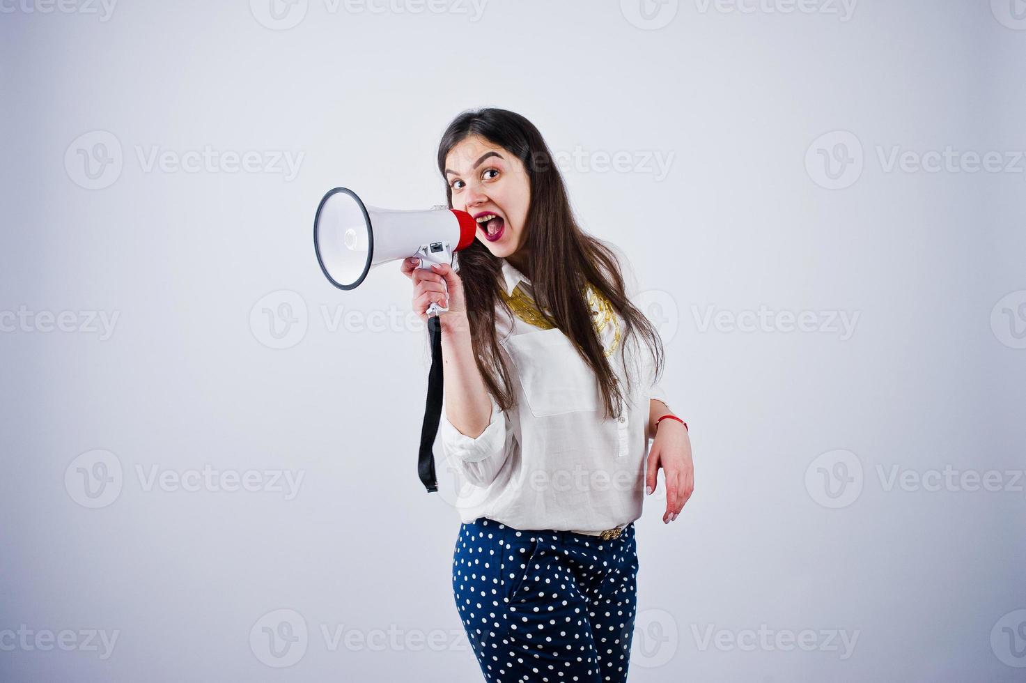 retrato de uma jovem de calça azul e blusa branca posando com megafone no estúdio. foto