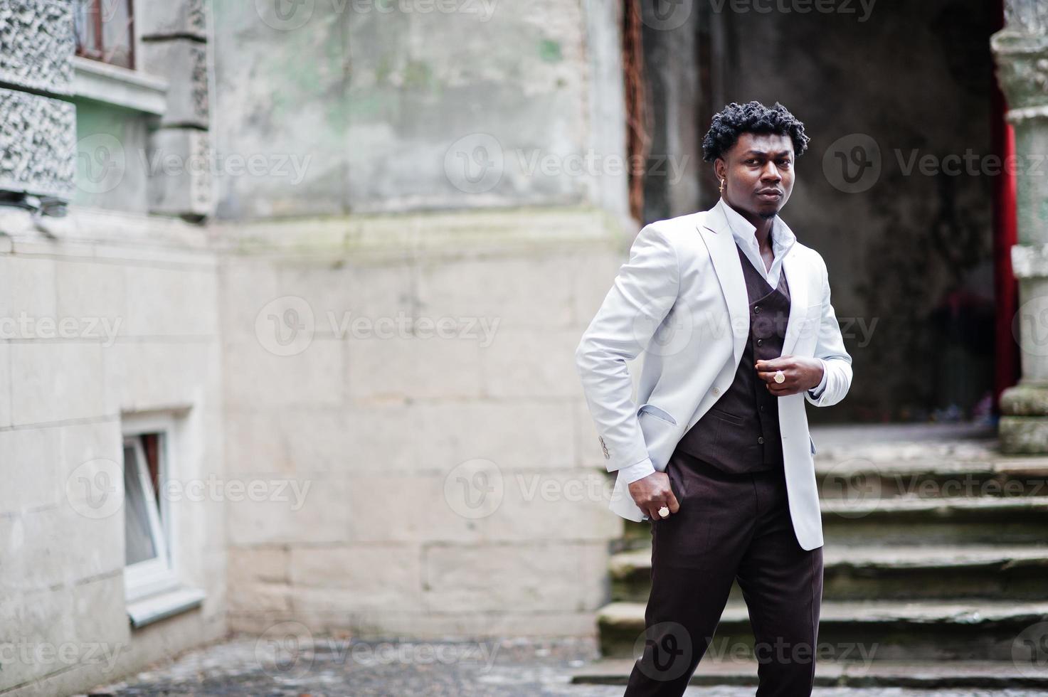 pensativo jovem cavalheiro afro-americano bonito em trajes formais. homem preto elegante modelo de casaco branco. foto