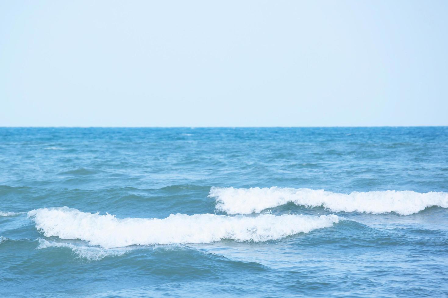 ondas do mar na onda do mar espirrando água da ondulação. fundo de água azul. deixe espaço para escrever o texto. foto