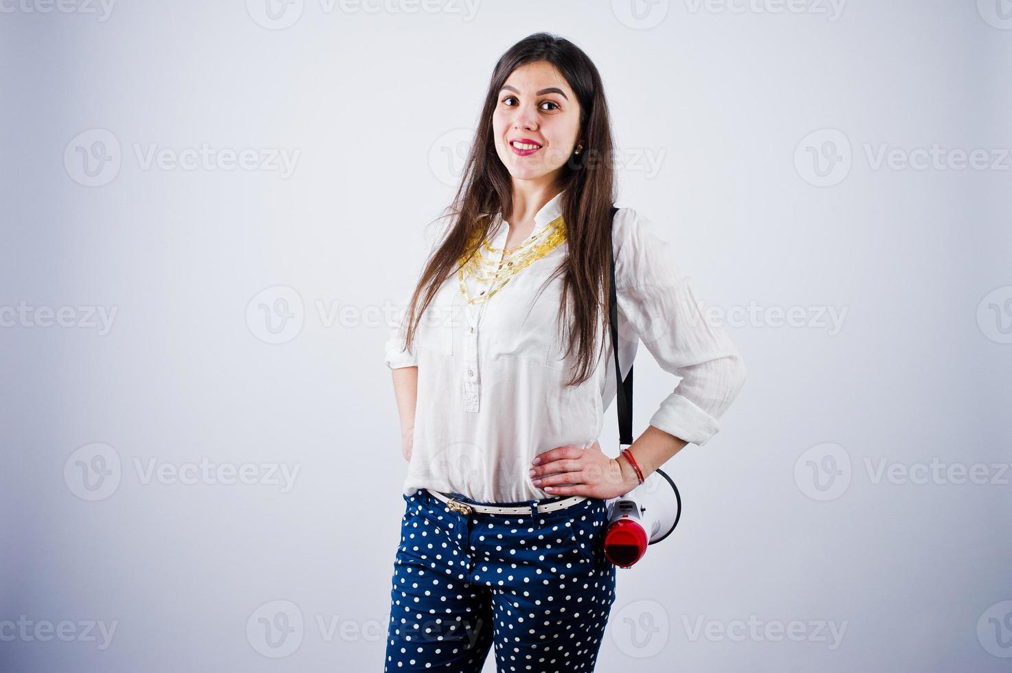 retrato de uma jovem de calça azul e blusa branca posando com megafone no estúdio. foto