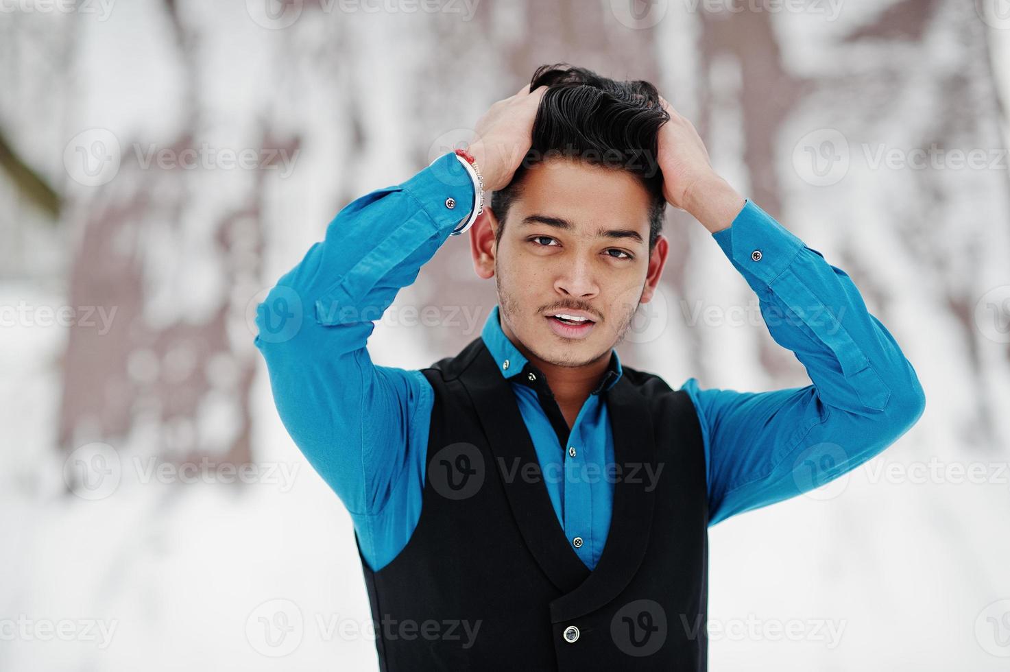 casual jovem indiano de camisa azul e colete preto posou em dia de inverno. foto