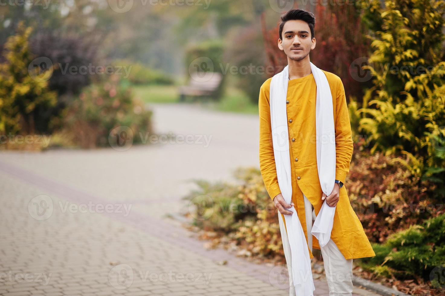 homem elegante indiano em roupas tradicionais amarelas com lenço branco posou ao ar livre. foto