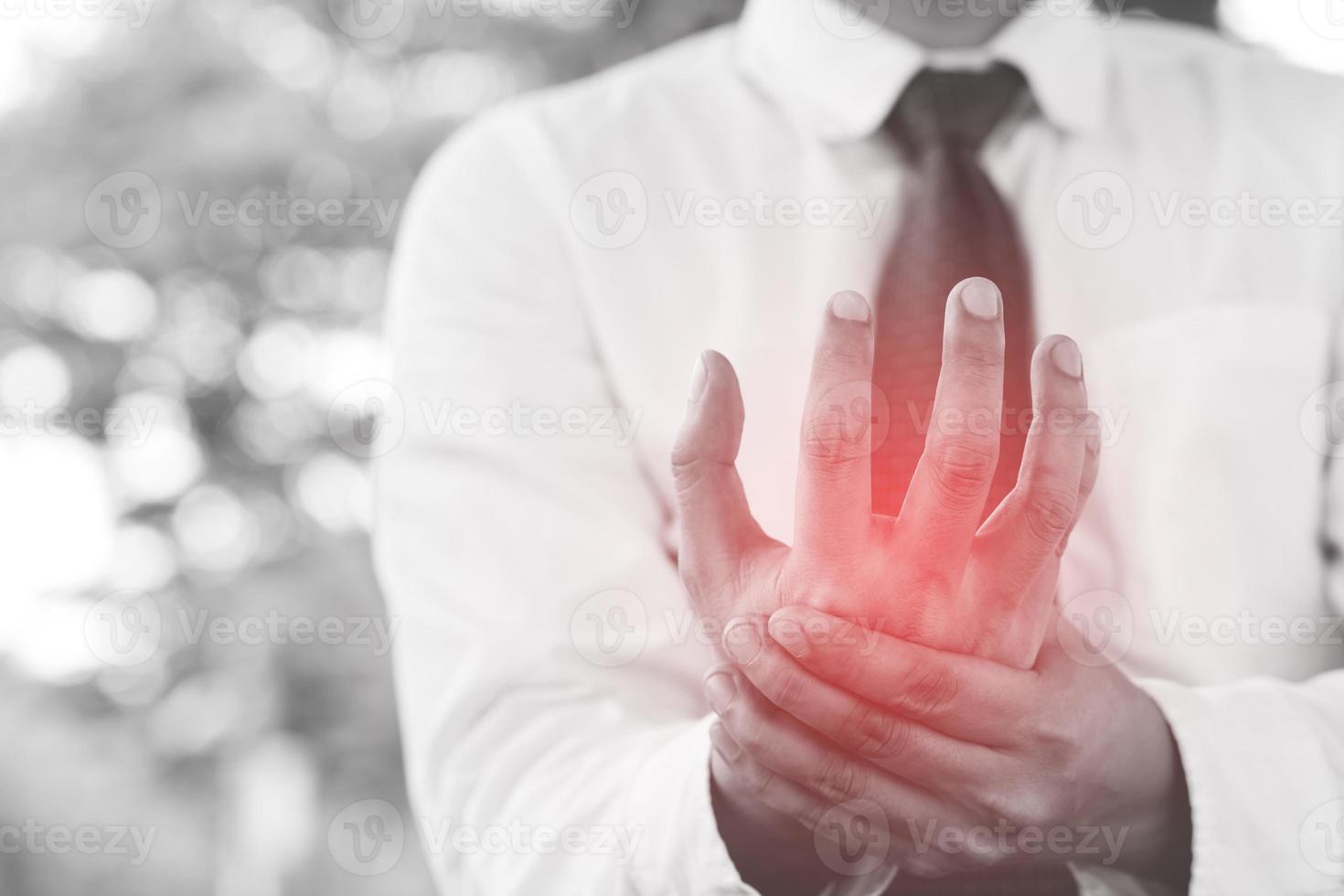 closeup de braços masculinos segurando seu pulso doloroso causado pela síndrome do escritório de trabalho prolongado. artrite reumatóide, gota ou entorse, fraqueza e formigamento. conceito de cuidados de saúde. foto