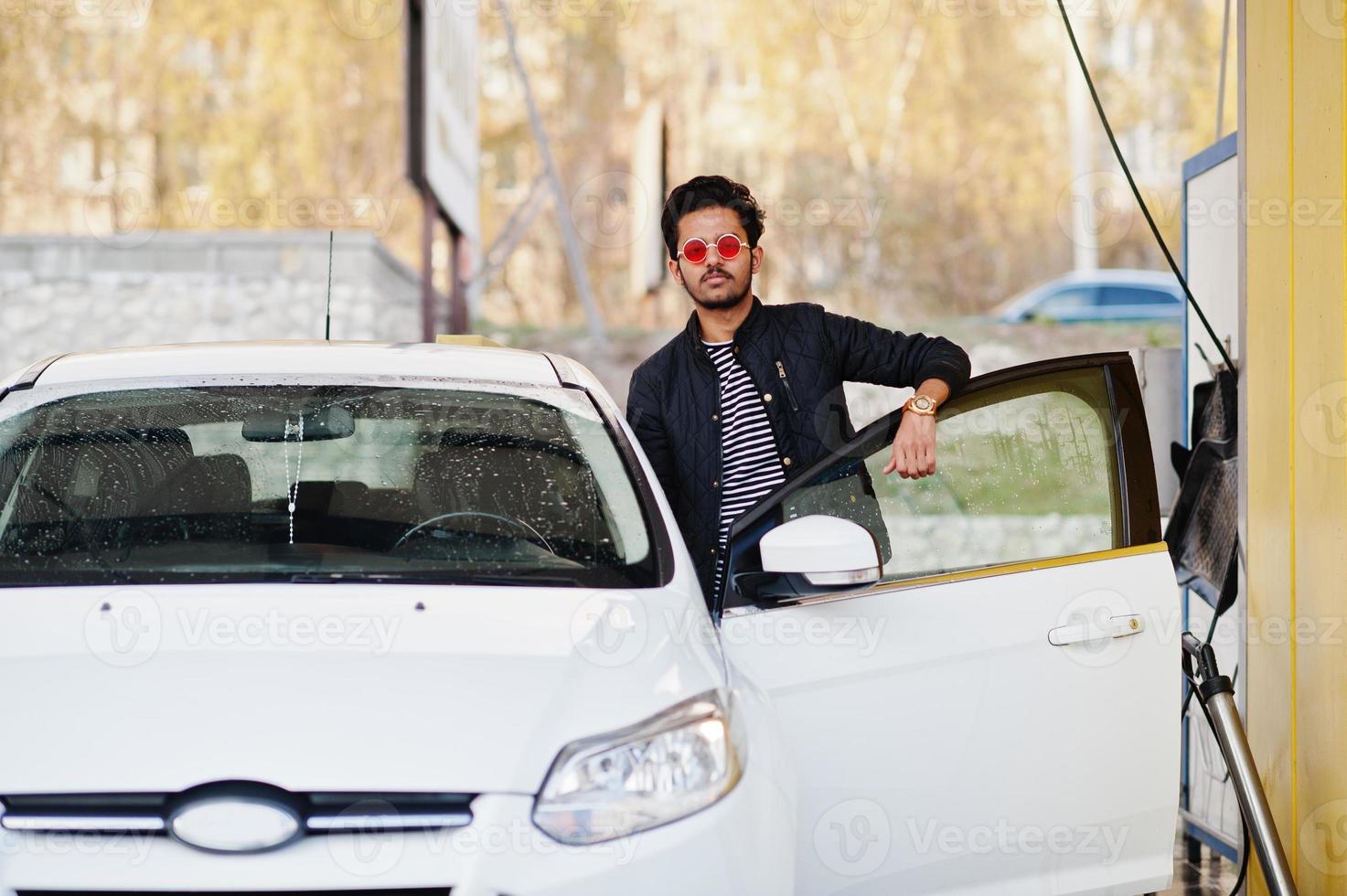 homem do sul da Ásia ou homem indiano lavando seu transporte branco na lavagem de carros. foto