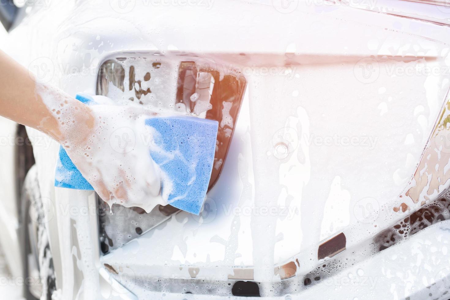 homem trabalhador de pessoas segurando a mão esponja azul e janela de limpador de espuma de bolha para lavar o carro. lavagem de carro de conceito limpa. deixe espaço para escrever mensagens. foto