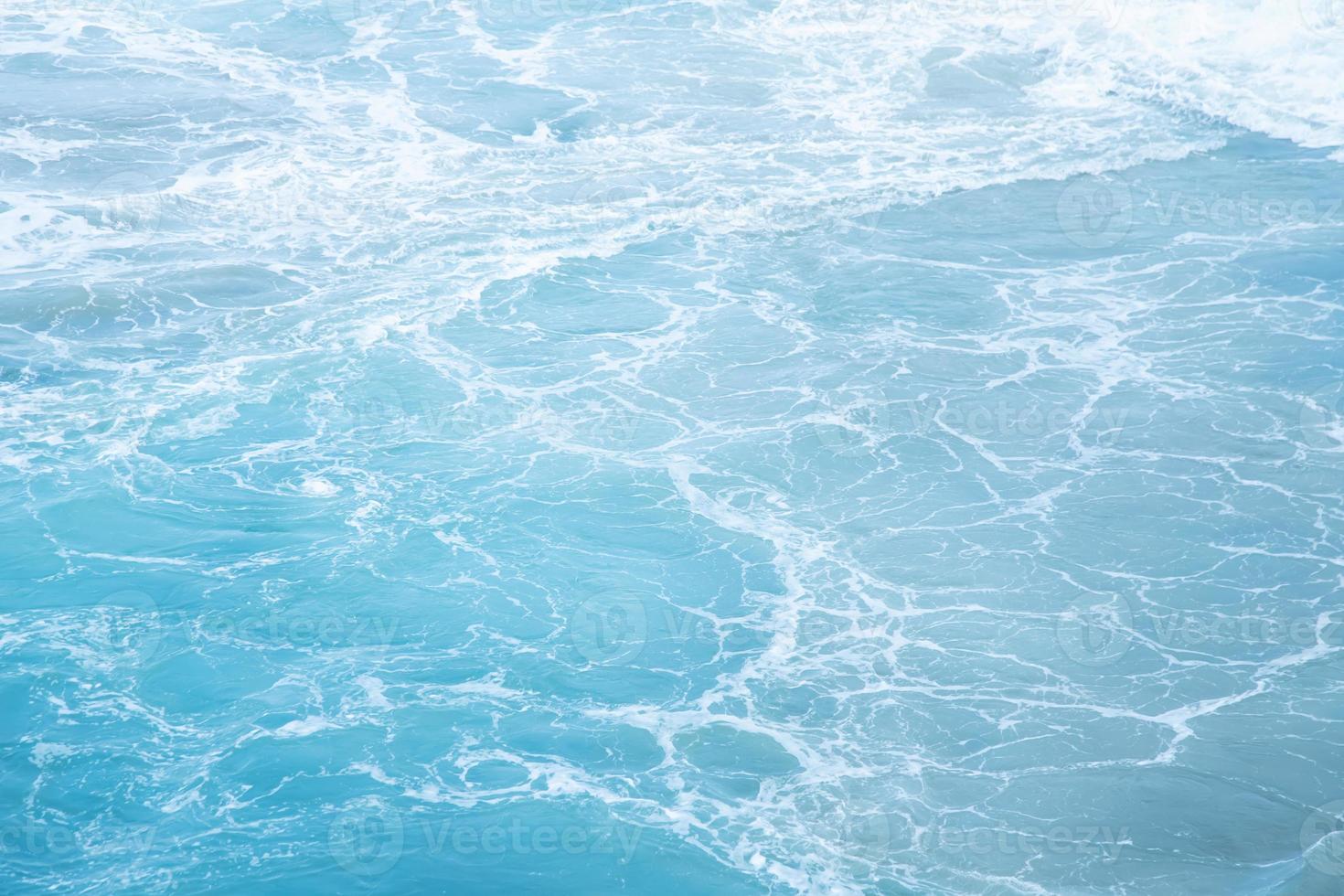 ondas do mar na onda do mar espirrando água da ondulação. fundo de água azul. deixe espaço para escrever um texto descritivo. foto