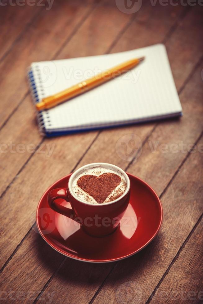 xícara de café com notebook em uma mesa de madeira. foto
