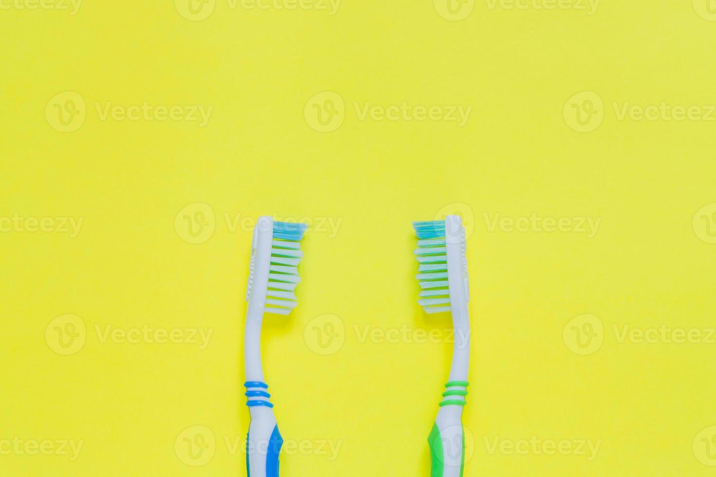 duas escovas de dentes em fundo amarelo. vista superior, configuração plana mínima. foto