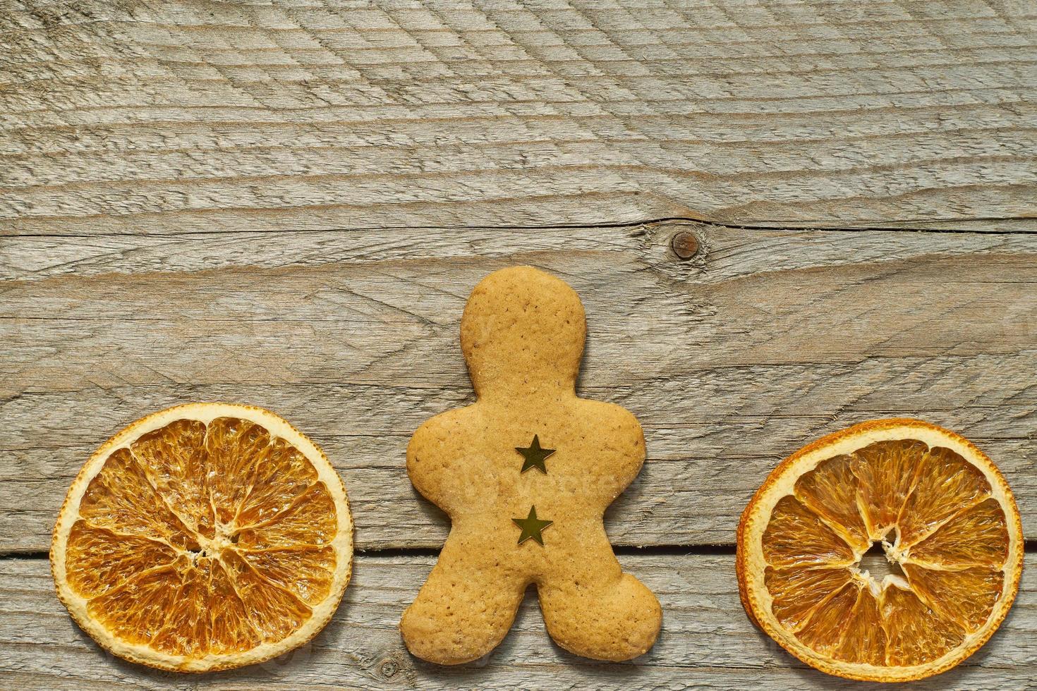 vista superior de fatias de laranja secas e homem de pão de gengibre em fundo de madeira. cartão festivo de natal com espaço de cópia para seus projetos foto