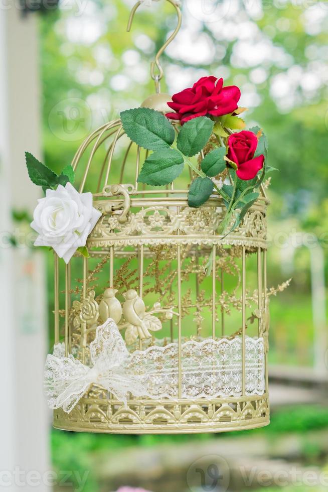 gaiola de pássaro decorativa ao ar livre. decoração de casamento com rosas vermelhas e brancas. foto