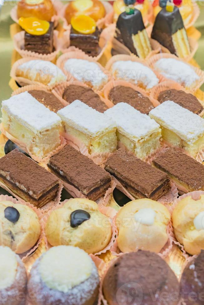 vitrine de pastelaria com variedade de mini sobremesas e bolos, barra de chocolate, foco seletivo foto