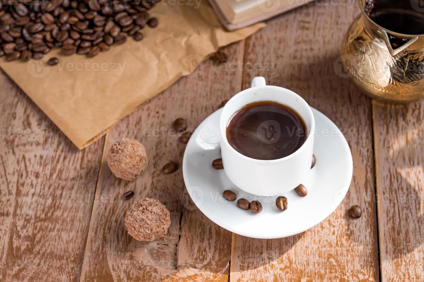 café fresco preparado em cezve tradicional café turco bebida matinal em copo branco ao lado de bolas de chocolate foto