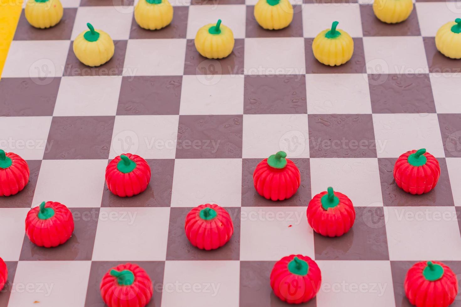 close-up do tabuleiro de xadrez com damas de abóbora, fundo colorido foto