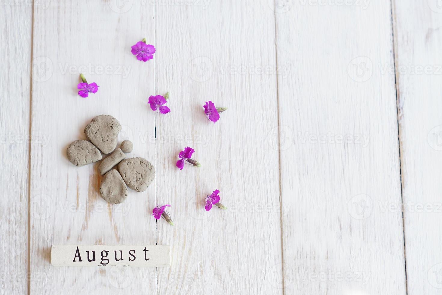 vista superior do calendário de madeira com sinal de agosto, borboleta de barro e flores cor de rosa. foto