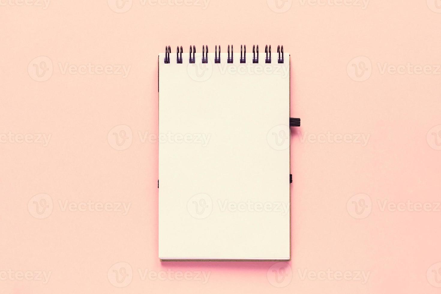 vista superior do caderno vazio aberto com capa de papel reciclado em fundo colorido rosa pastel foto