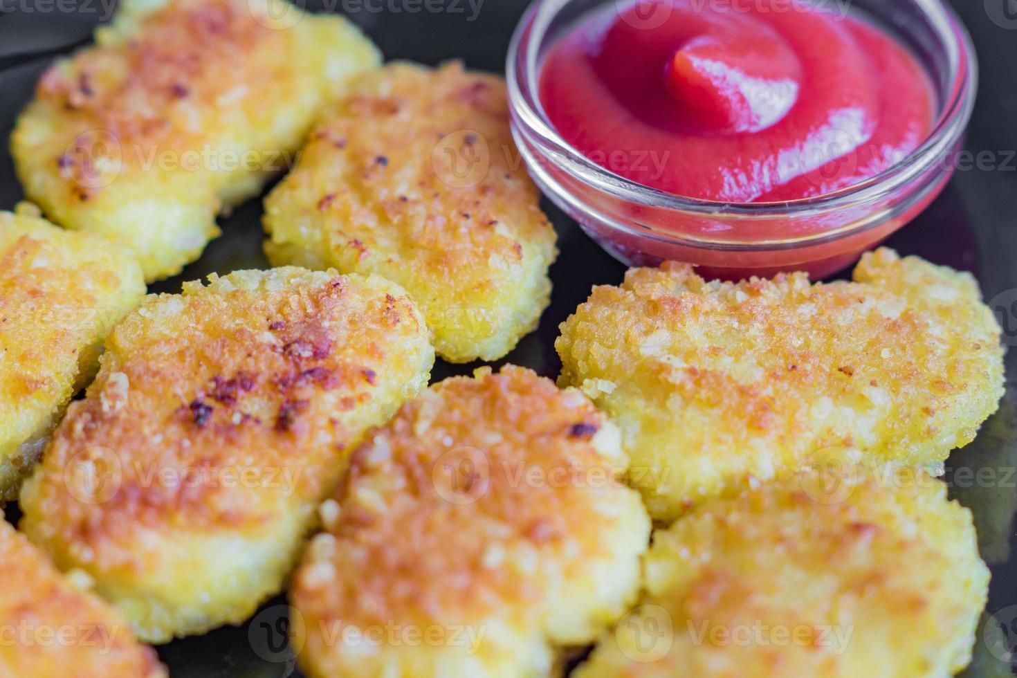 nuggets de frango crocante frito com ketchup em um prato preto foto