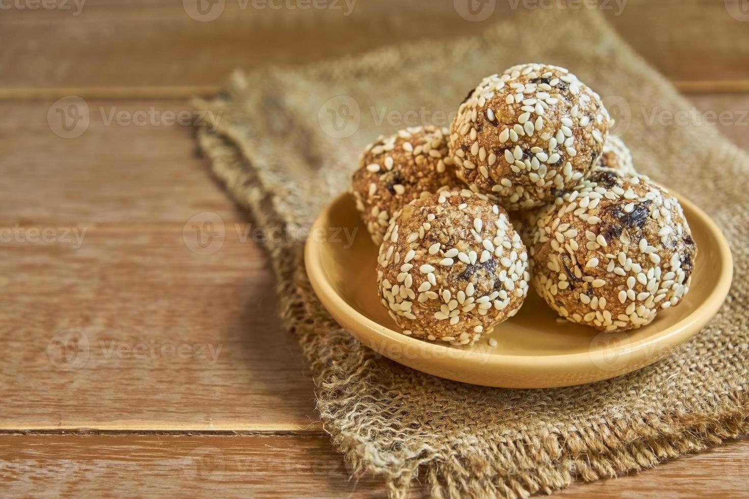 mordidas de granola de energia orgânica saudável com nozes, cacau, ameixas, gergelim e mel - lanche cru vegano e vegetariano em fundo de madeira foto