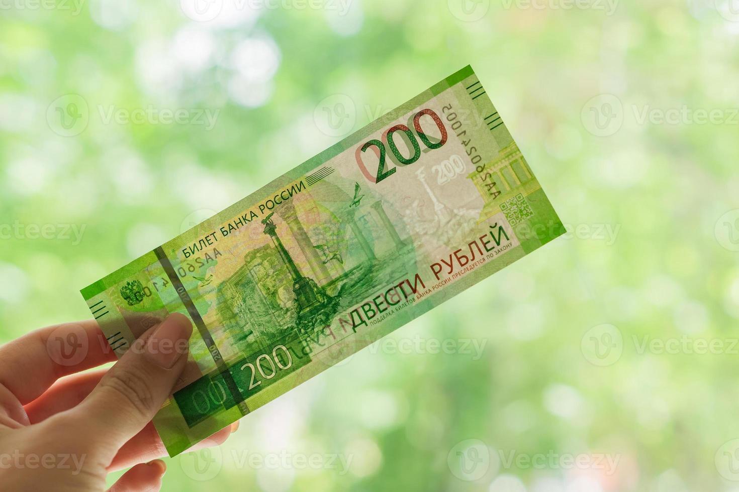 mão feminina segurando a nova nota russa contra a janela. duzentos rublos. dinheiro em papel. foto