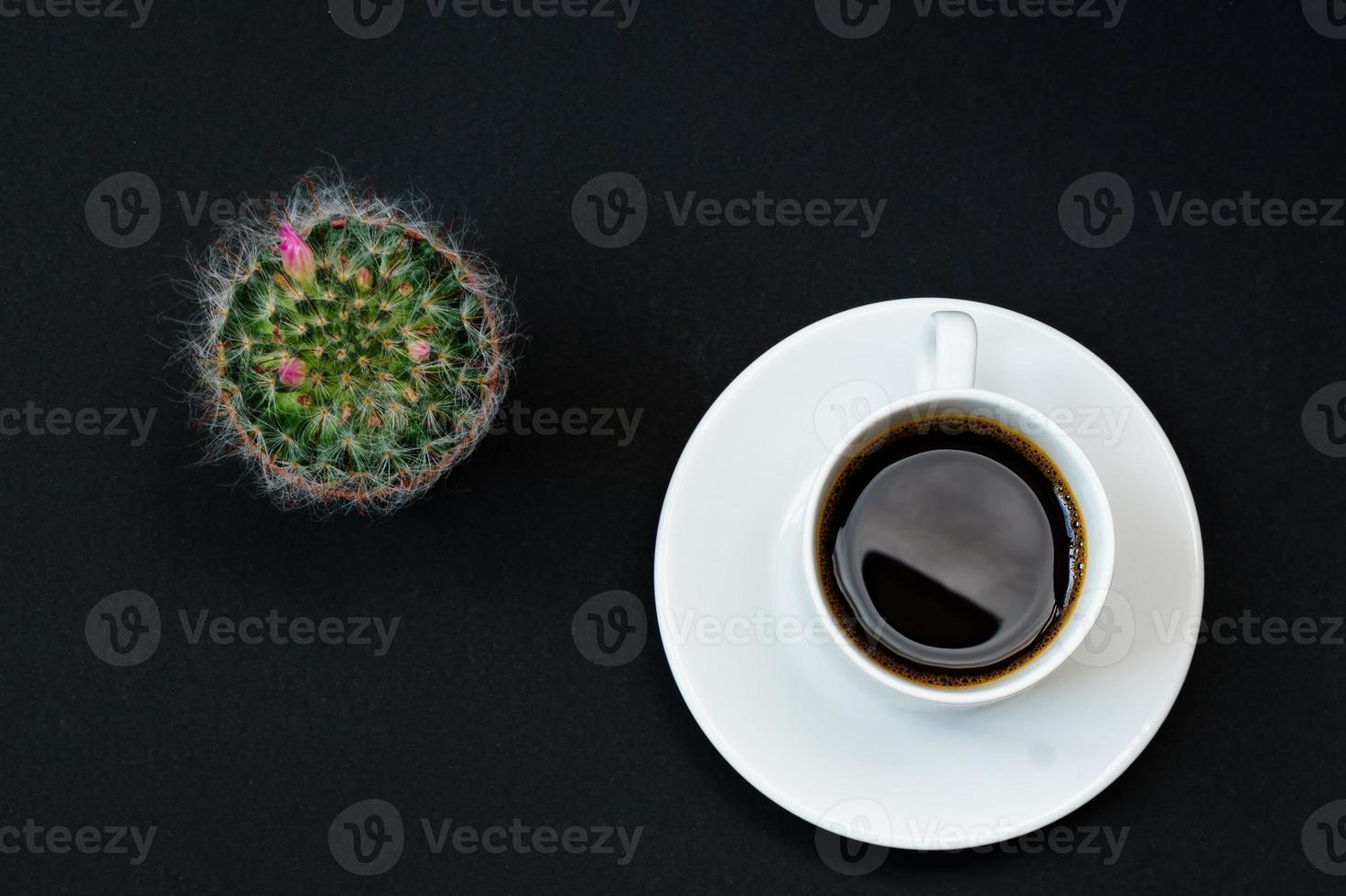 xícara de café preto e cacto florescendo em fundo preto, vista superior, copie o espaço. foto