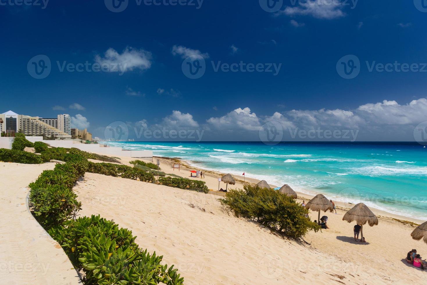 guarda-chuvas em uma praia de areia com água azul em um dia ensolarado perto de cancun, méxico foto