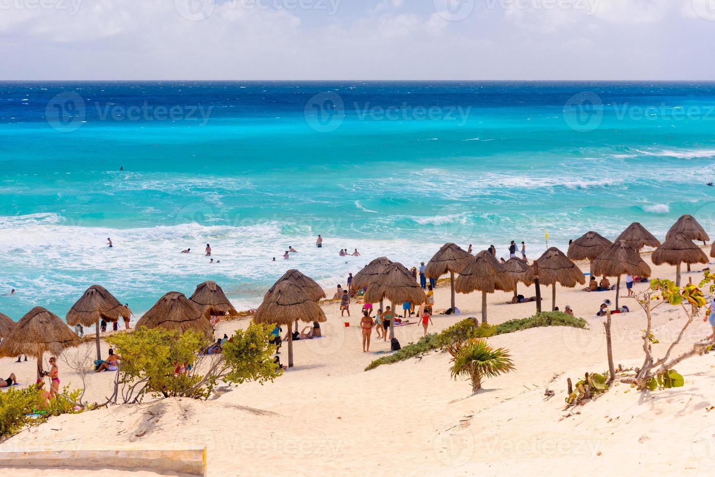 guarda-chuvas em uma praia de areia com água azul em um dia ensolarado perto de cancun, méxico foto