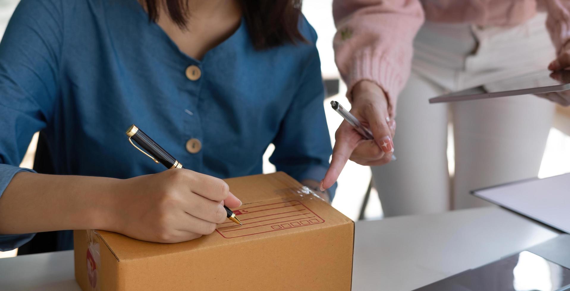 retrato de proprietários de pequenas empresas iniciantes, duas mulheres asiáticas verificam pedidos on-line que vendem produtos trabalhando com caixas trabalho freelance em home office, pequenas empresas on-line de pequenas e médias empresas foto